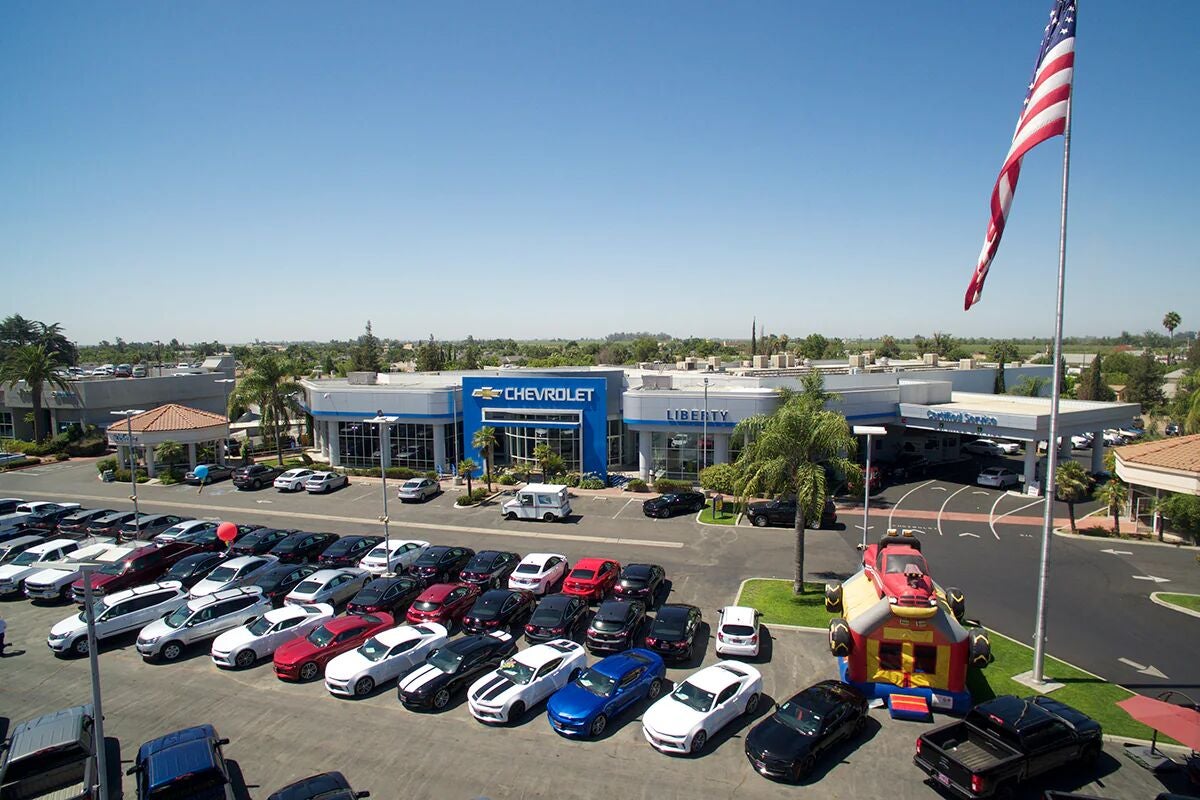 An aerial view of a Chevrolet dealership and surrounding parking lots filled with new cars, under a clear sky.